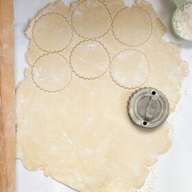 A cookie cutter cutting circles out of donut dough