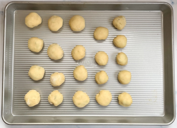 Donut holes being proofed on a baking sheet