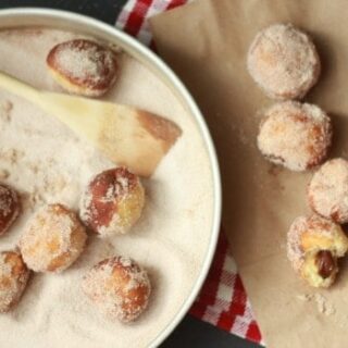 Mini Donuts in a pan being rolled in cinnamon sugar