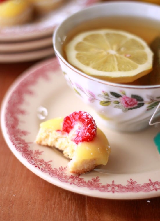 Lemon Curd and Raspberry Tea Cookie on a plate with a bite taken out beside a cup of tea