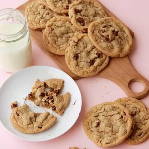 Chocolate chip cookies on wooden platter, one cookie on a plate