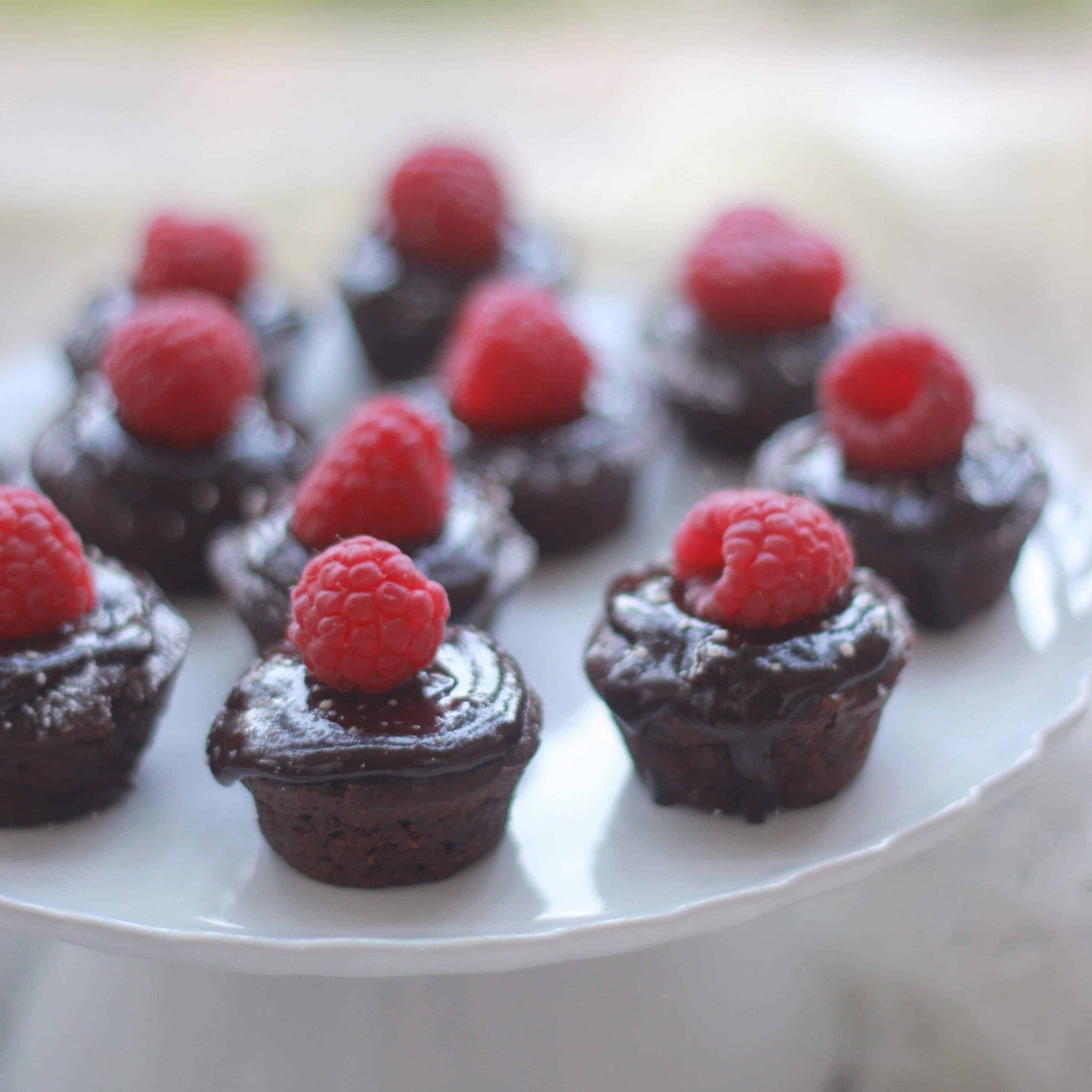 Mini Flourless Chocolate Tortes with a raspberry on top of each on a cake stand