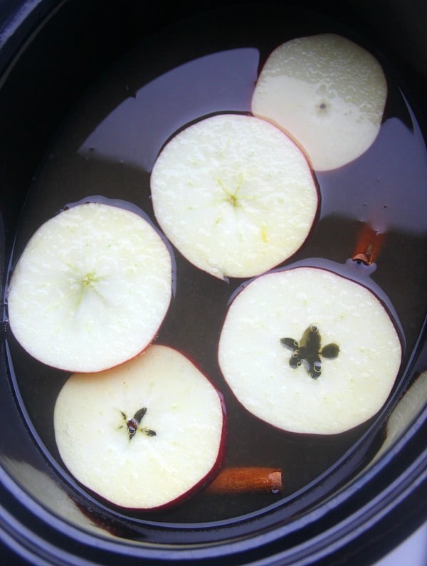 Apple cider still in the crockpot with fresh apple slices for garnish