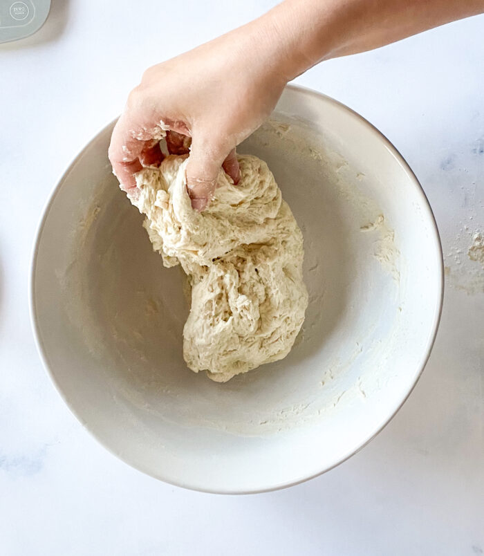 mixing bread dough in a bowl by hand
