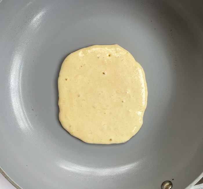 Pancake cooking on griddle, only a few bubbles.