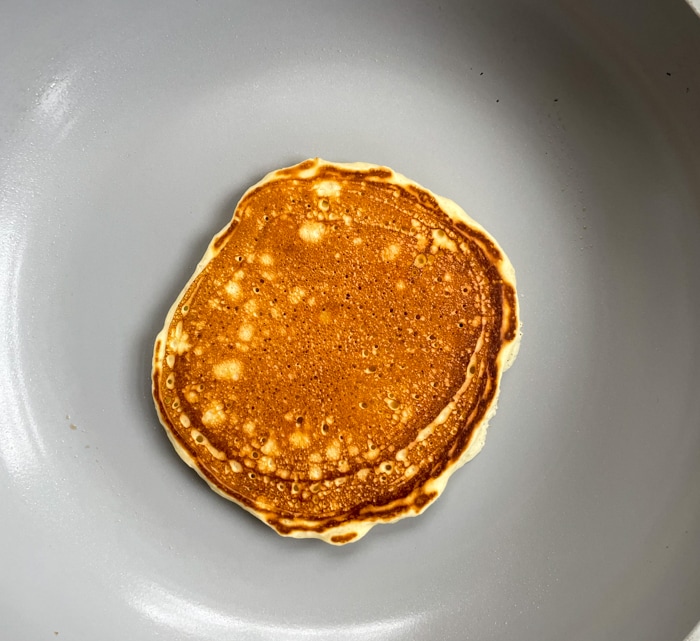Flipped golden brown pancake on griddle.