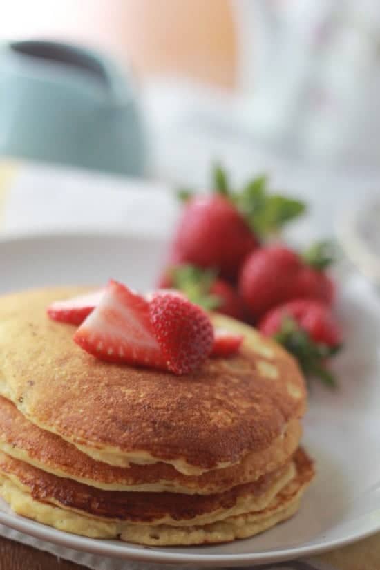 Stack of pancakes on a plate with strawberries on top