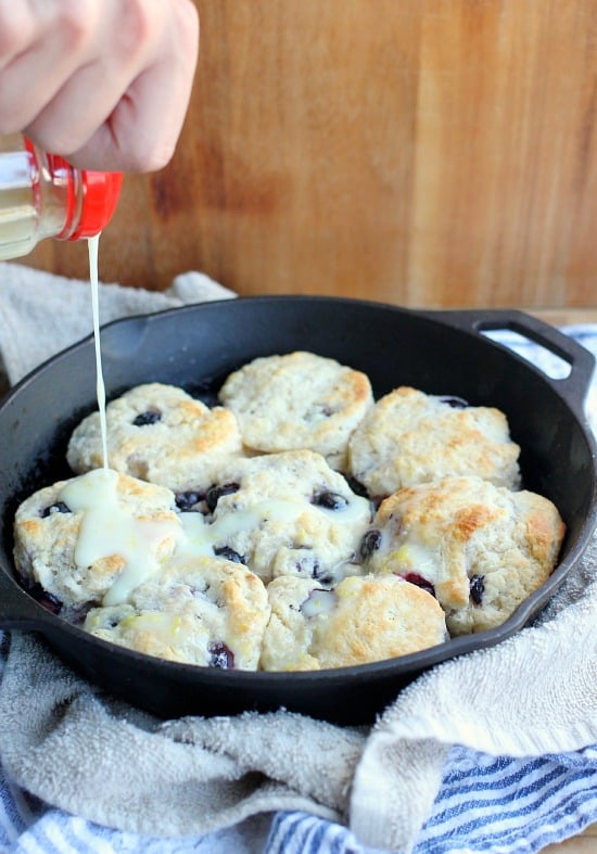 Blueberry biscuits being drizzled with lemon glaze