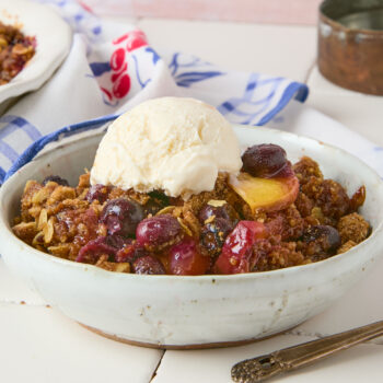 Blueberry Peach Crisp in a small bowl with ice cream on top