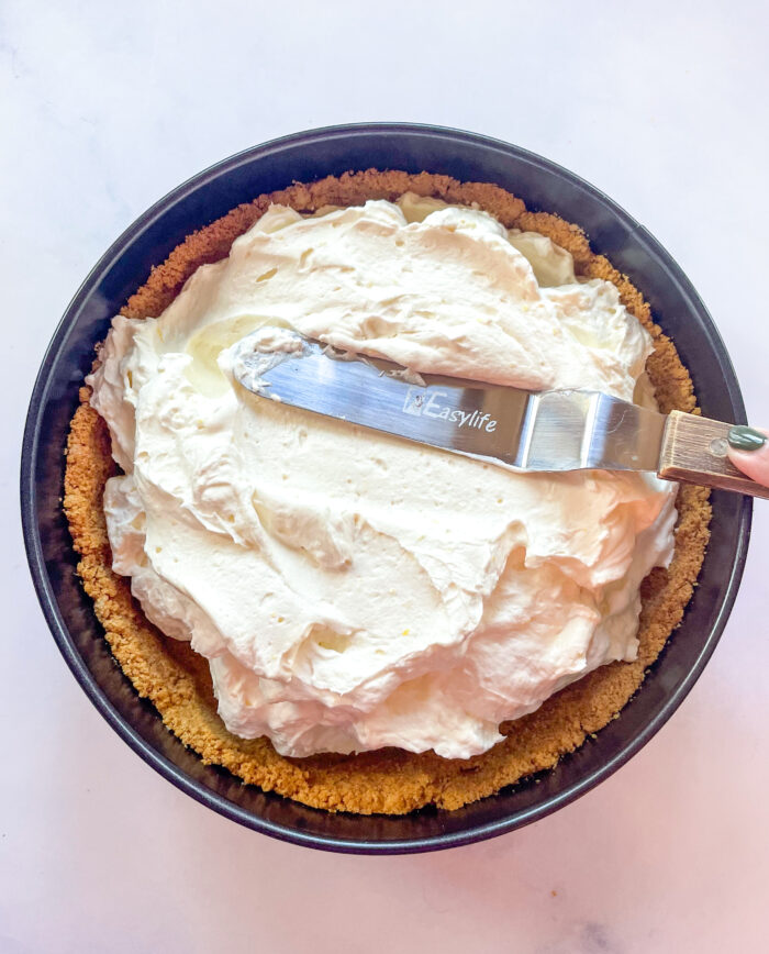 lemon cheesecake filling being spread into crust