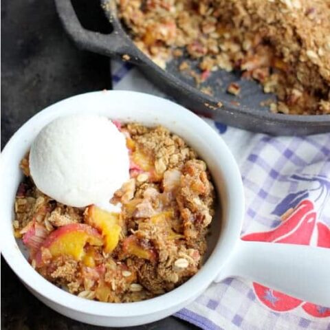 A serving of Peach Rhubarb Skillet Crisp in a bowl with ice cream