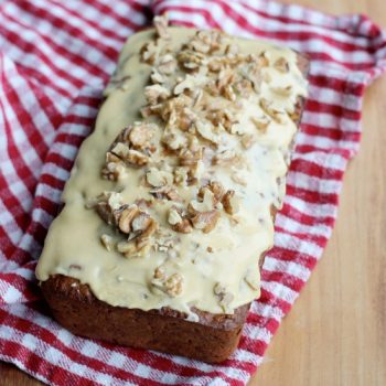 A loaf of Banana Walnut Bread with Burnt Sugar and Whiskey Frosting and chopped walnuts on top
