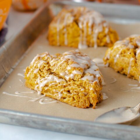 sheet pan with pumpkin scones with cinnamon glaze drizzled on top