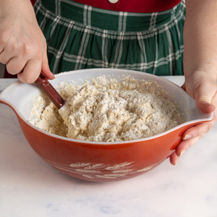 Bread dough being mixed in a bowl with a spatula