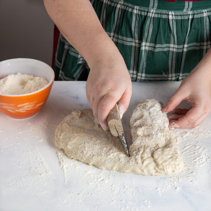 Bread dough being divided with a bench knife