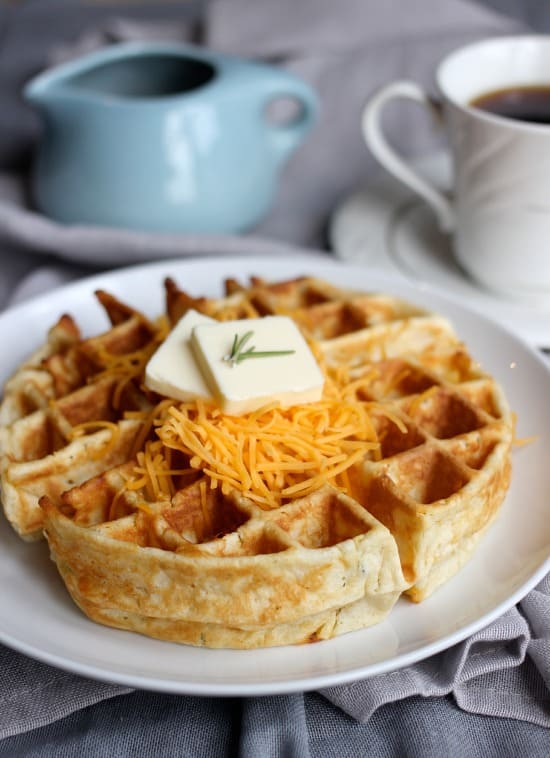 Cheddar and Rosemary waffle with shredded cheddar and pad of butter on top
