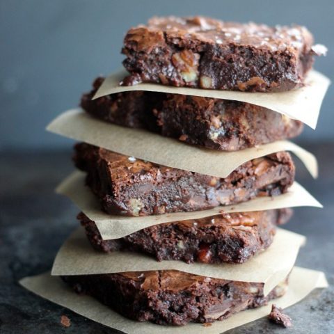 Ultimate Fudge Brownies stacked up with parchment paper between them