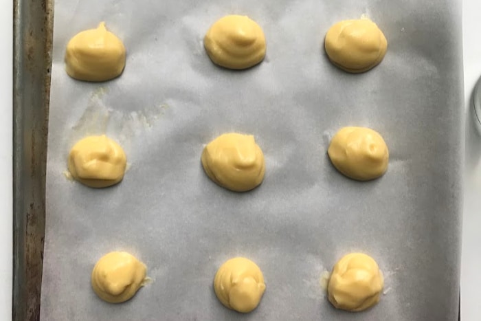 Choux batter after being piped into rounds on a baking sheet