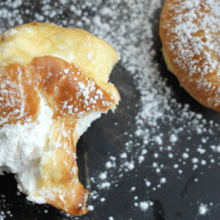 A cream puff with a bite taken out filled with cream