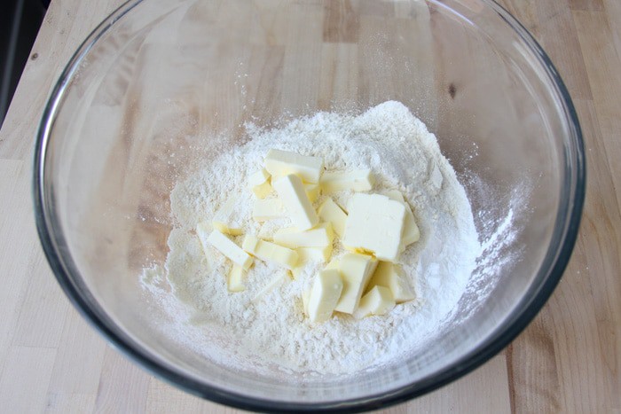 Pieces of butter in the bowl with the dry ingredients for the biscuits.