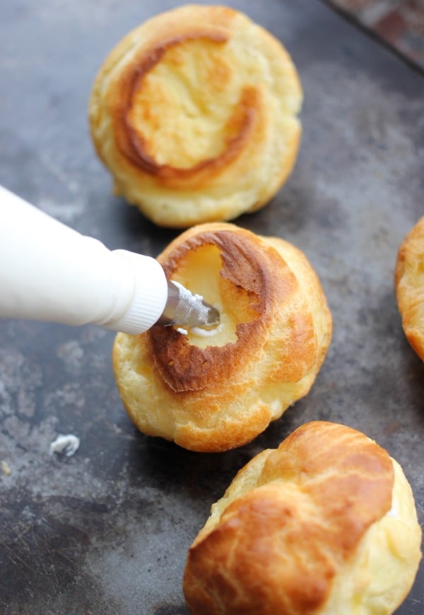 A pastry bag filled with cream filling up the bottom of the cooked cream puff
