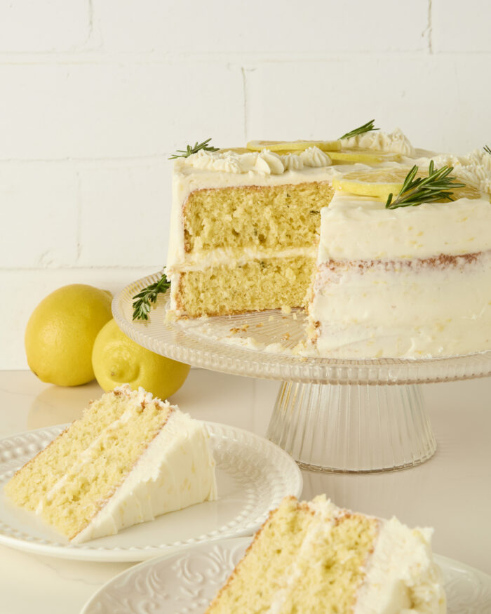 slices of lemon cake on plates with the cut cake behind them