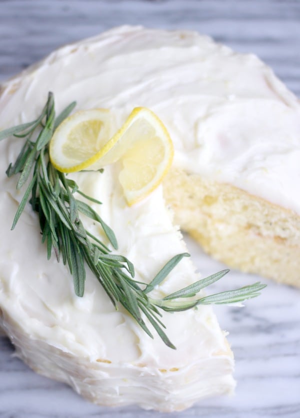 Fluffy Lemon-Rosemary Cake with Lemon Cream Cheese Frosting with a slice taken out