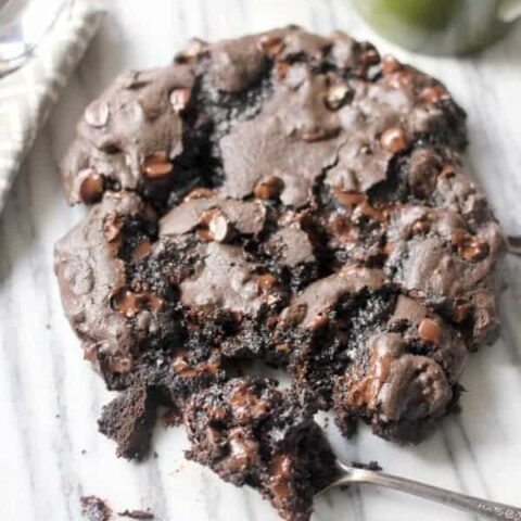 Huge Dark Chocolate Cookie with Espresso and Toasted Pecans with a bite taken out with a spoon