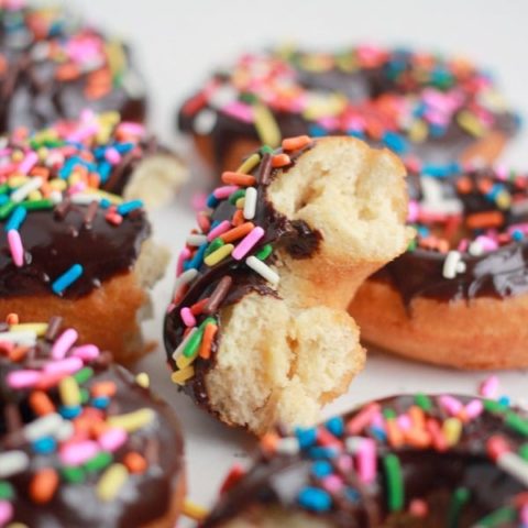 Cake Donuts with Chocolate Ganache and colorful sprinkles, one with a bite taken out