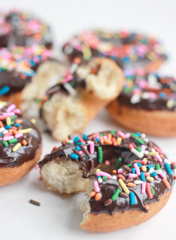 Cake Donuts with Chocolate Ganache and colorful sprinkles, one with a bite taken out