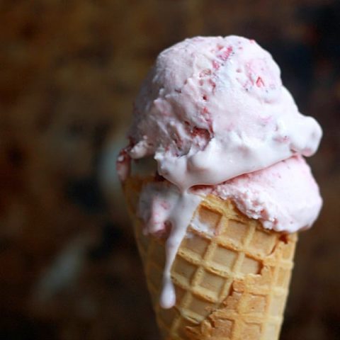 Roasted Strawberry Cheesecake Ice Cream pilled high in a waffle cone