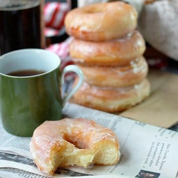 Stacked glazed donuts with cup of coffee and newspaper