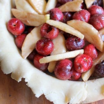 Unbaked pie crust filled with cherries and apples