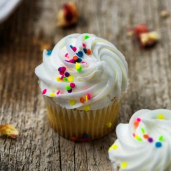 Classic white cupcake with white buttercream frosting and rainbow sprinkles