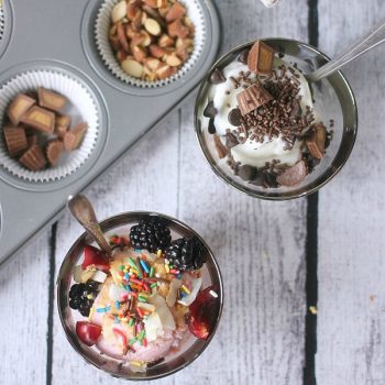 Frozen yogurt in cups topped with fruit, sprinkles, nuts, chocolate, etc.