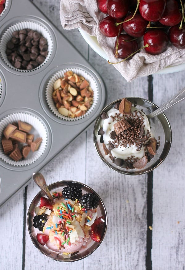 Frozen yogurt in cups topped with fruit, sprinkles, nuts, chocolate, etc. 