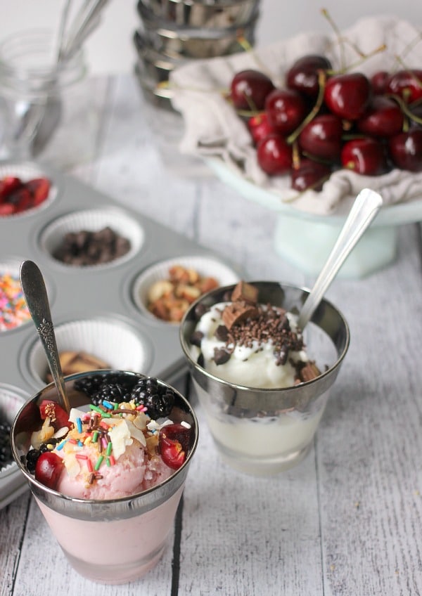 Frozen yogurt in cups topped with fruit, sprinkles, nuts, chocolate, etc. 