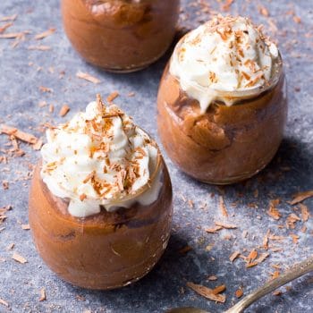 Individual portions of chocolate mousse in parfait cups topped with whipped cream and chocolate shavings.
