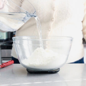 Pouring water into a bowl of flour