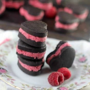 Heart shaped Homemade Oreos with Raspberry Filling stacked up on a plate