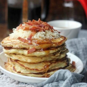 Savory Bacon Cheddar Pancakes stacked up topped with cheddar and bacon crumbles