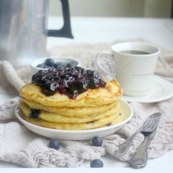 A stack of Fluffy Blueberry Buttermilk Pancakes topped with blueberry compote