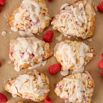raspberry scones with glaze and fresh berries on a sheet pan