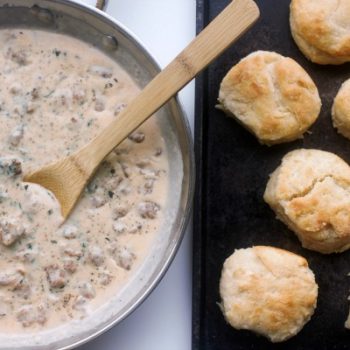 A pan of classic sausage gravy beside a pan of freshly baked biscuits
