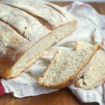 Rustic baked Yeast Bread lightly floured with a slice cut off