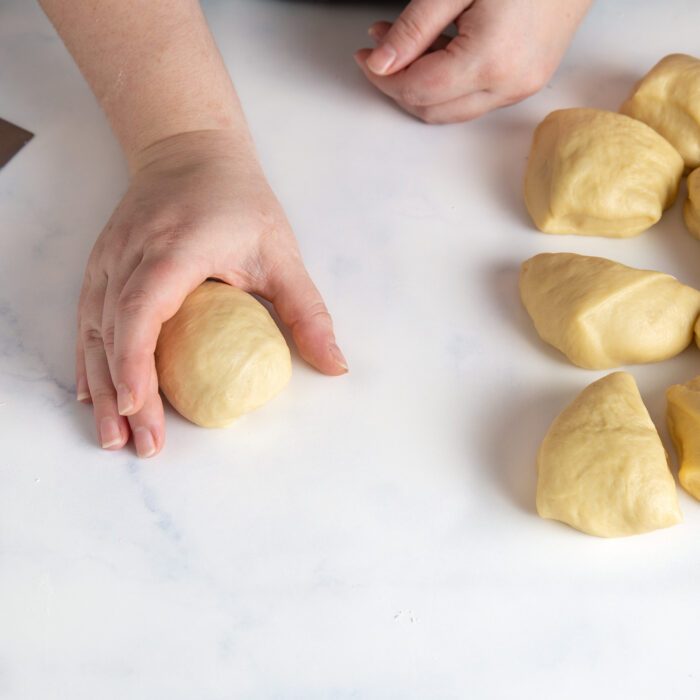 Shaping dinner rolls by placing them on the countertop and rolling the ball under your hand.