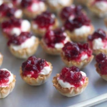 Mini tart shells filled with cheesecake filling and a tiny bit of cranberry