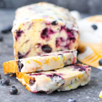 Loaf of blueberry bread with lemon glaze with a few slices cut out of it.