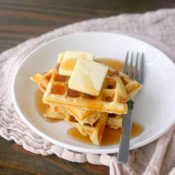 A stack of waffles with syrup and butter