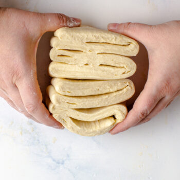 Holding a section of quick puff pastry showing the layers made in the dough